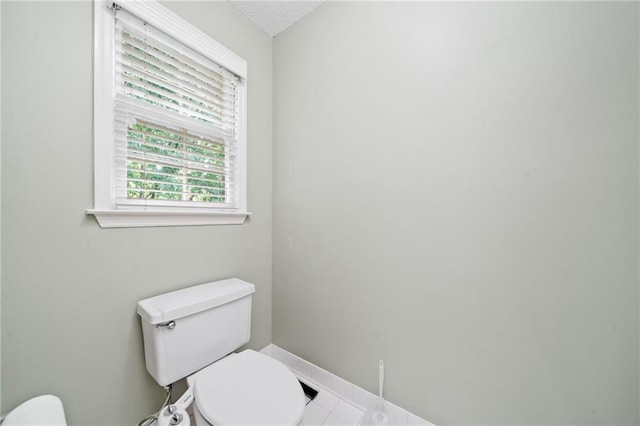 half bath featuring toilet and baseboards