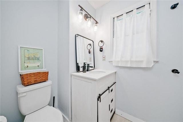 bathroom featuring toilet, vanity, and baseboards