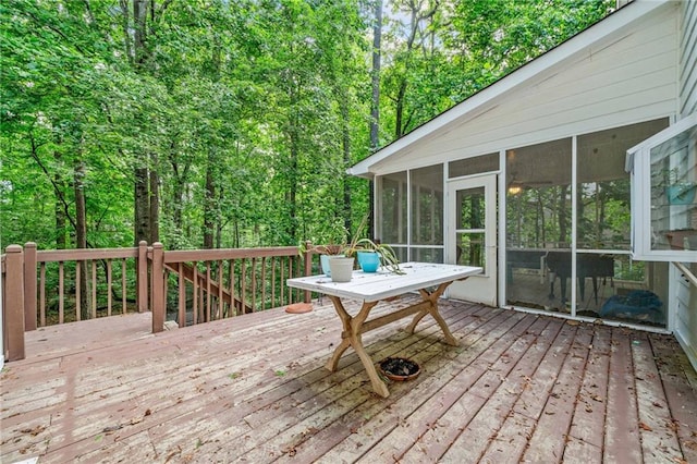 wooden deck with a sunroom and a wooded view