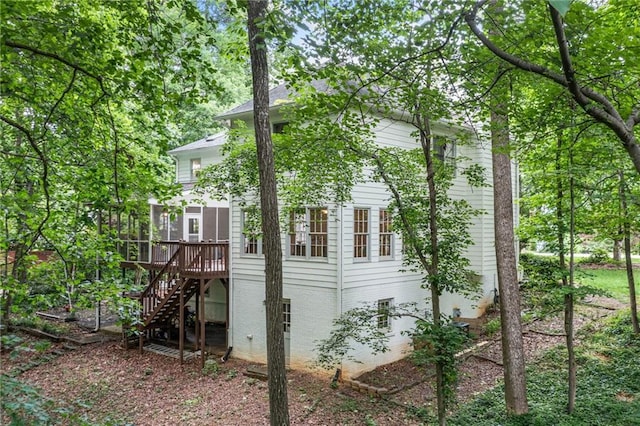 view of home's exterior featuring stairway, a deck, brick siding, and a sunroom