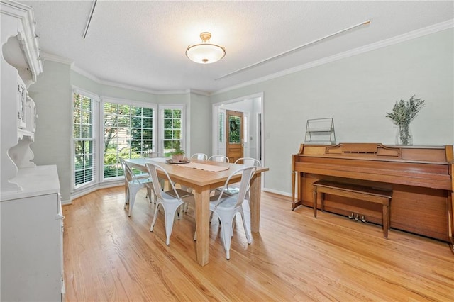 dining room with light wood-style flooring, crown molding, a textured ceiling, and baseboards