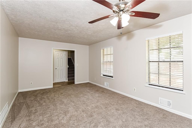 carpeted spare room featuring ceiling fan, a healthy amount of sunlight, and a textured ceiling