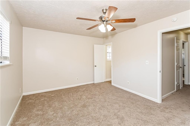 carpeted spare room featuring a textured ceiling and ceiling fan