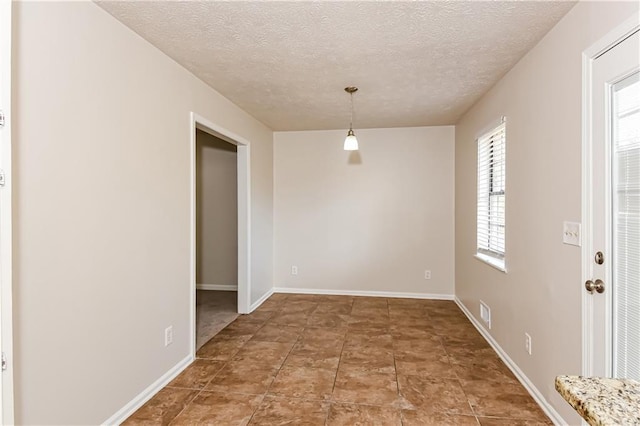 unfurnished dining area featuring a textured ceiling