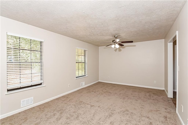 unfurnished bedroom with ceiling fan, light carpet, and a textured ceiling