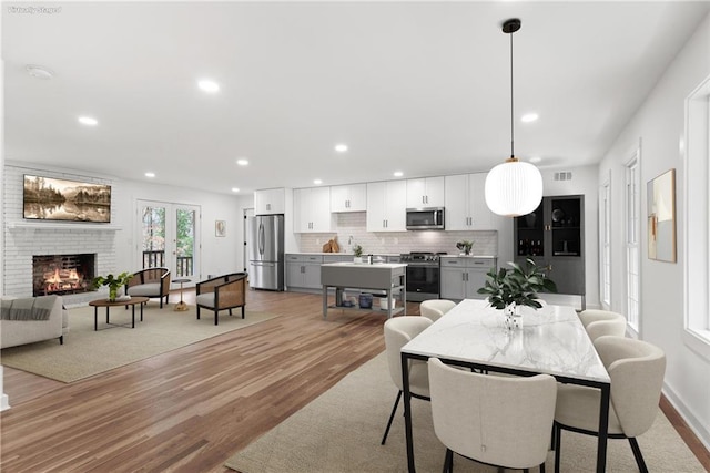 dining room featuring recessed lighting, visible vents, a fireplace, and light wood finished floors