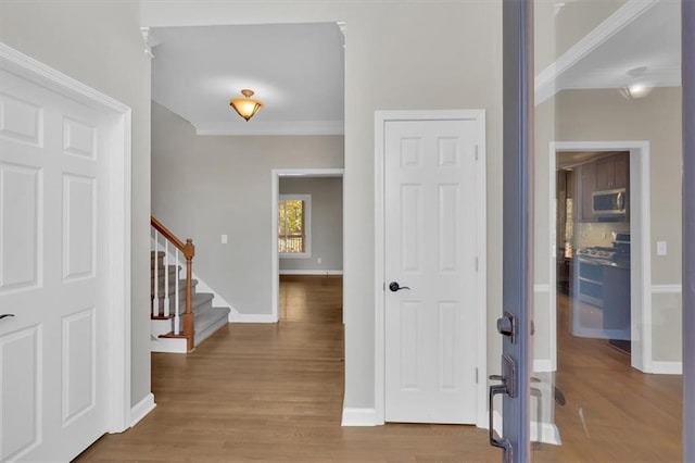 entryway with ornamental molding and hardwood / wood-style flooring