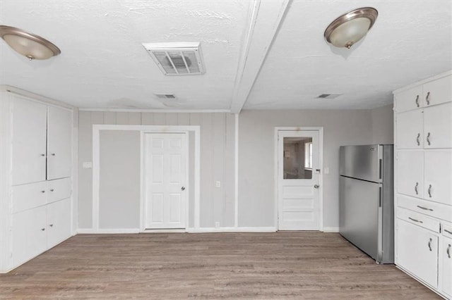 kitchen featuring white cabinetry, light wood-style flooring, visible vents, and freestanding refrigerator