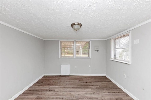 spare room with ornamental molding, a textured ceiling, baseboards, and wood finished floors