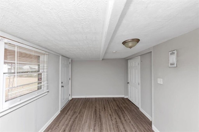 spare room featuring a textured ceiling, baseboards, and wood finished floors