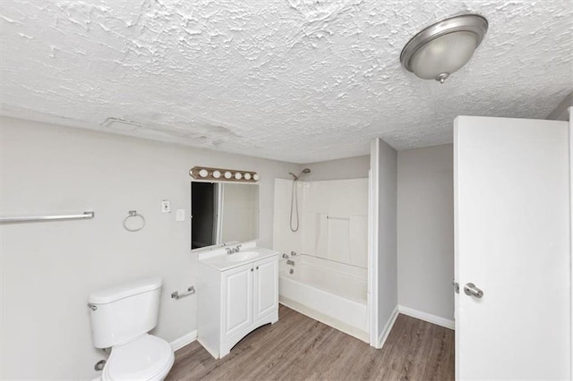 bathroom featuring vanity, wood finished floors, a textured ceiling, shower / bathing tub combination, and toilet