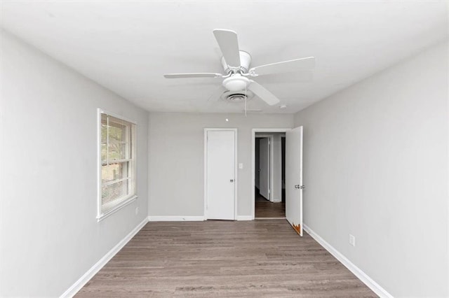 unfurnished room with ceiling fan, visible vents, baseboards, and wood finished floors