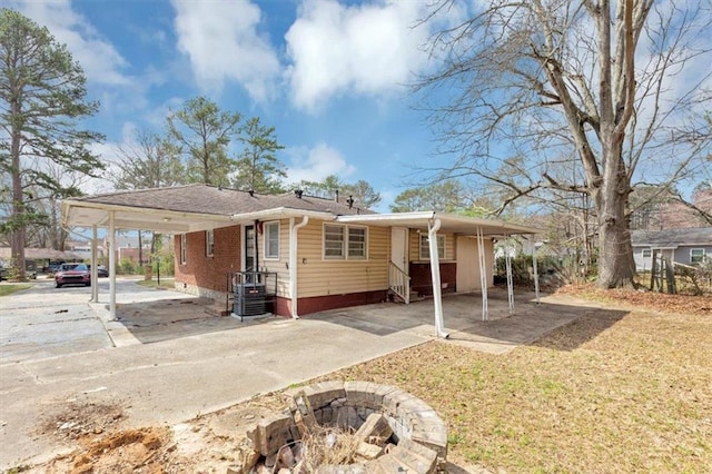 exterior space with entry steps, an attached carport, a fire pit, and driveway