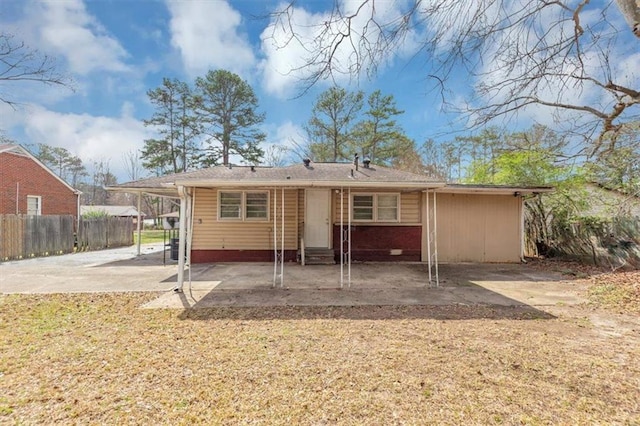 rear view of property with a carport, entry steps, a patio, and fence