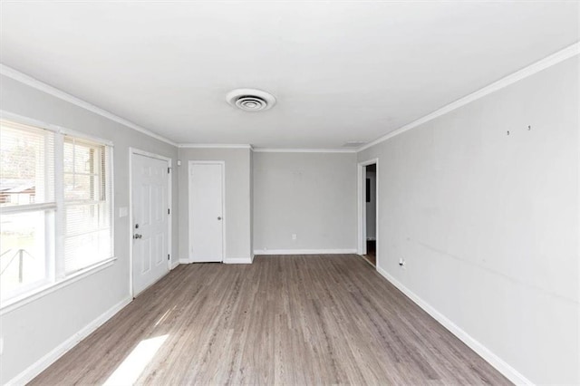 unfurnished room featuring visible vents, ornamental molding, baseboards, and wood finished floors