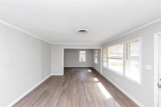 spare room with wood finished floors, crown molding, baseboards, and visible vents