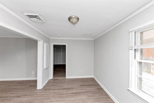 unfurnished room featuring visible vents, baseboards, wood finished floors, and crown molding