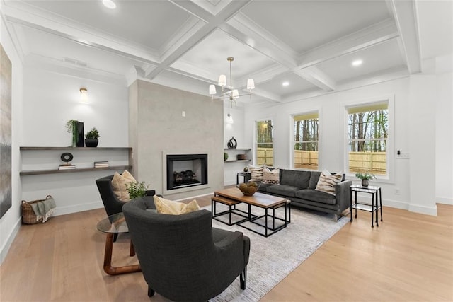 living room featuring a fireplace, light wood-style floors, a notable chandelier, and coffered ceiling