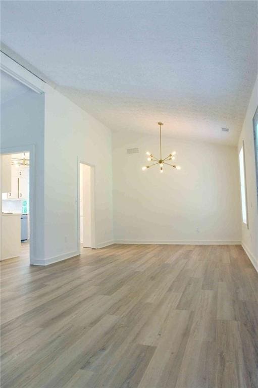 5974 SW Four Winds Dr SW, Lilburn, GA 30047 - unfurnished room featuring lofted ceiling, a chandelier, light wood-type flooring, and a textured ceiling