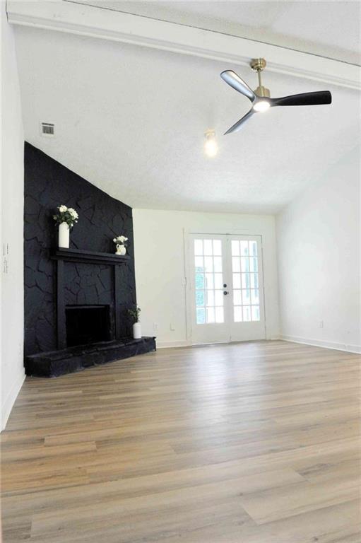 5974 SW Four Winds Dr SW, Lilburn, GA 30047 - unfurnished living room with light wood-style flooring, a fireplace, a ceiling fan, and french doors