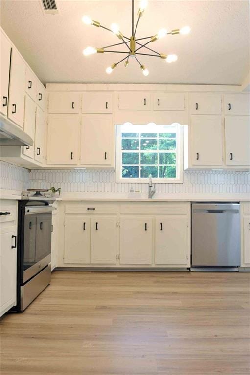 5974 SW Four Winds Dr SW, Lilburn, GA 30047 - kitchen featuring stainless steel appliances, under cabinet range hood, white cabinetry, light countertops, and a chandelier