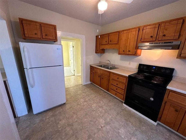 kitchen with electric range, sink, white fridge, and a textured ceiling