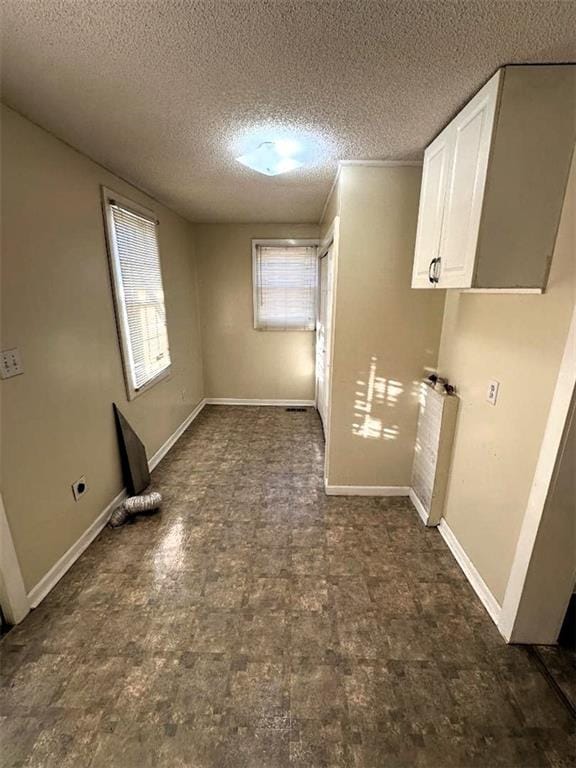 clothes washing area featuring electric dryer hookup, cabinets, a textured ceiling, and radiator