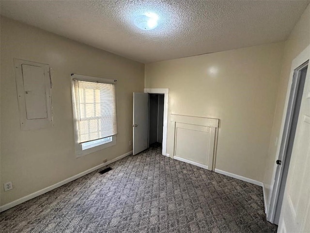 unfurnished bedroom with dark colored carpet, a textured ceiling, and electric panel