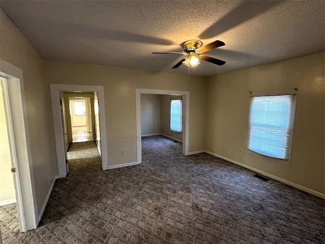 unfurnished bedroom with ceiling fan, a textured ceiling, and dark colored carpet