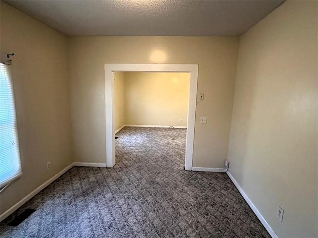 carpeted spare room with a textured ceiling