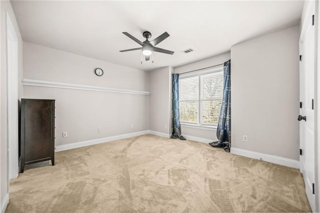 carpeted empty room with visible vents, baseboards, and ceiling fan