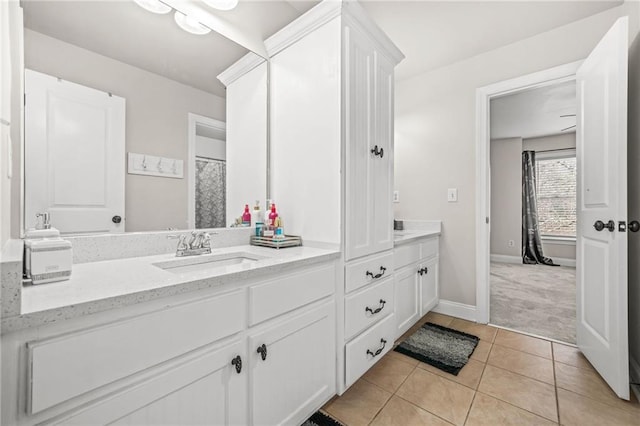 bathroom with double vanity, tile patterned floors, baseboards, and a sink