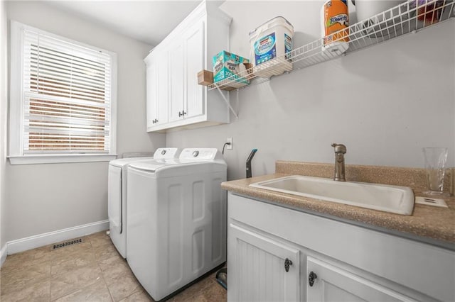 washroom featuring visible vents, a sink, washer and dryer, cabinet space, and baseboards