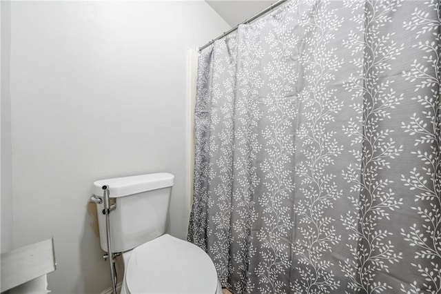 bathroom with curtained shower and toilet