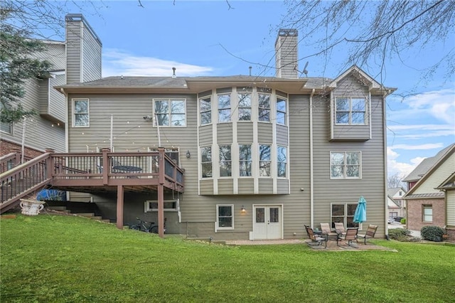 rear view of property with a patio, a lawn, a deck, and a chimney