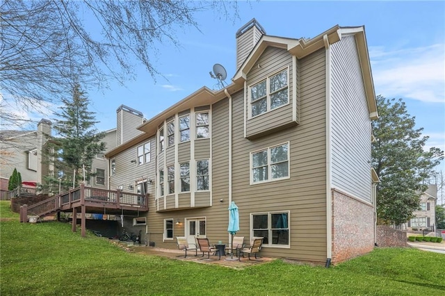 back of house with a wooden deck, a patio area, a lawn, and a chimney