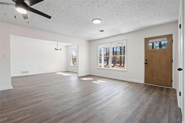 foyer featuring ceiling fan with notable chandelier, dark hardwood / wood-style flooring, and a textured ceiling