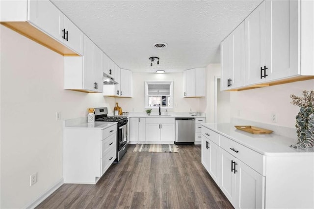 kitchen with stainless steel appliances, a textured ceiling, dark wood-type flooring, and white cabinetry