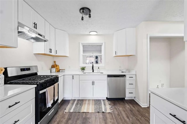 kitchen featuring stainless steel appliances, sink, white cabinets, a textured ceiling, and dark hardwood / wood-style floors