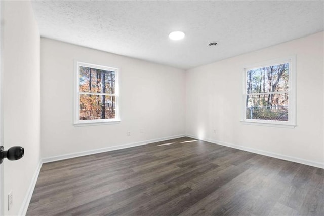 empty room with a textured ceiling and dark hardwood / wood-style flooring