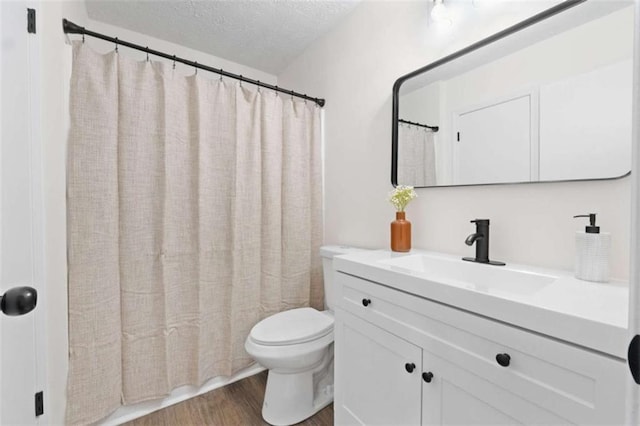 bathroom with curtained shower, a textured ceiling, hardwood / wood-style floors, toilet, and vanity