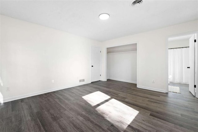 unfurnished bedroom featuring dark hardwood / wood-style flooring, ensuite bathroom, and a closet