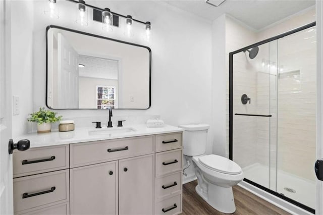 bathroom with toilet, hardwood / wood-style flooring, walk in shower, crown molding, and vanity