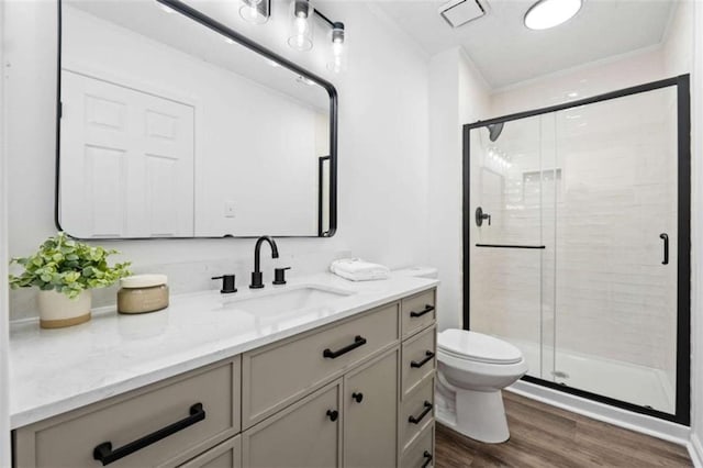 bathroom featuring toilet, wood-type flooring, vanity, and a shower with door