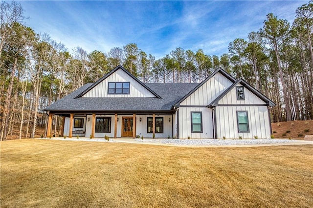 modern inspired farmhouse featuring covered porch, a shingled roof, board and batten siding, and a front yard