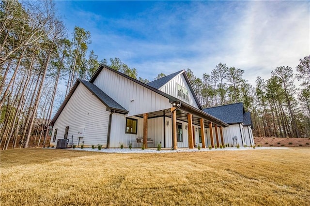 exterior space featuring board and batten siding, central AC, a front lawn, and roof with shingles