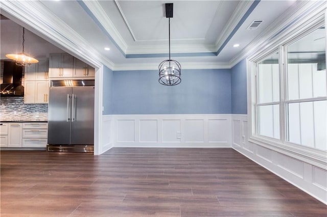 unfurnished dining area with visible vents, a raised ceiling, dark wood finished floors, and a chandelier