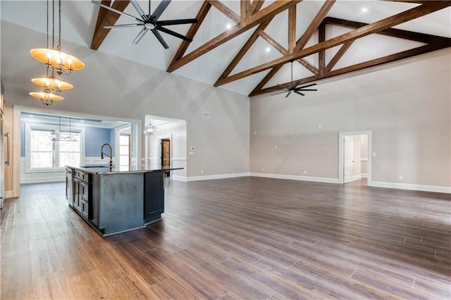 kitchen featuring an island with sink, ceiling fan with notable chandelier, open floor plan, and decorative light fixtures