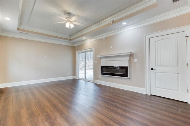 unfurnished living room featuring a tray ceiling, dark wood finished floors, a ceiling fan, a glass covered fireplace, and baseboards