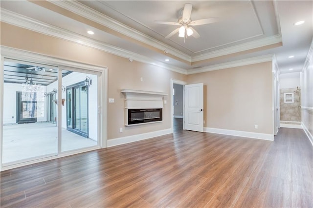 unfurnished living room with ceiling fan, a raised ceiling, wood finished floors, and a glass covered fireplace